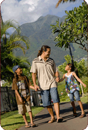 man holding girl and boys hands walking down the park